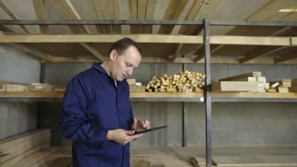 一名拿着平板电脑的男子正在家具厂散步 检查木堆 — 图库视频影像