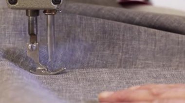 Mobilya üretim süreci. Karanlık bir kat büyük bir kadında closeup malzeme için bir dikiş makinesi ile kanepe dikiş.