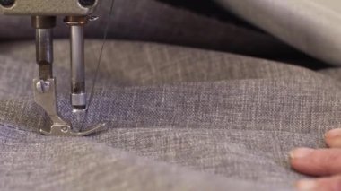Mobilya üretim süreci. Karanlık bir kat büyük bir kadında closeup malzeme için bir dikiş makinesi ile kanepe dikiş.