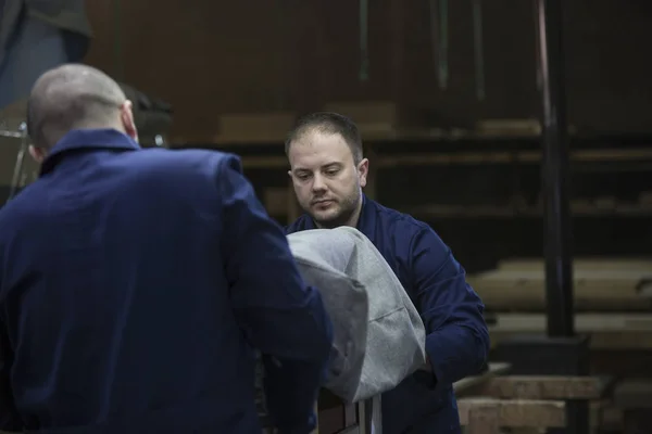 Twee jonge mannen in een meubelfabriek samengesteld enerzijds van de Bank — Stockfoto