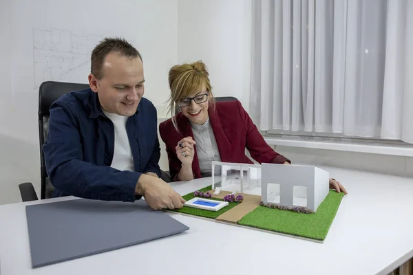 Два архітектори дивляться на модельний будинок в офісі — стокове фото