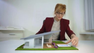 Ofiste mimar bir ev modelinde havuz ayarlayarak masada oturuyor. Göz Gözcüler ile düşünceli tasarımcı proje hakkında düşünme. Etrafında hareketli parçalar, modelle oynama.