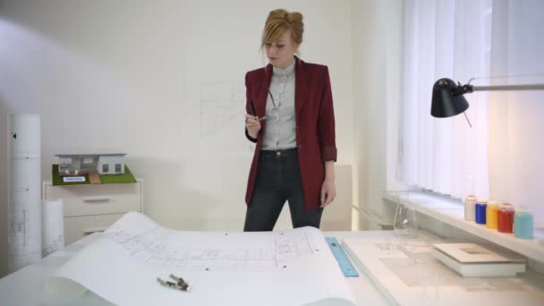 テーブルの Houseat の青写真を見ている眼鏡を持った女性建築家 — ストック動画