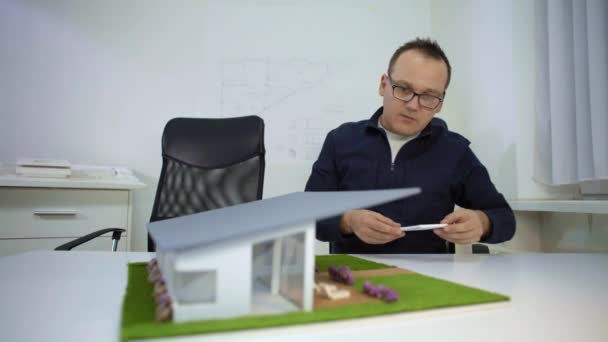 Arkitekt Som Sitter Ved Skrivebordet Justerer Bassengkanten Husmodell Omtenksom Designer – stockvideo