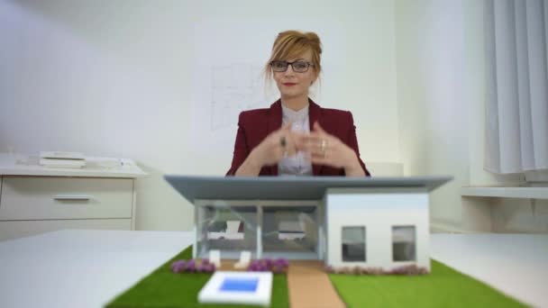 Junge Architektin Büro Sitzt Schreibtisch Und Blickt Über Ein Hausmodell — Stockvideo