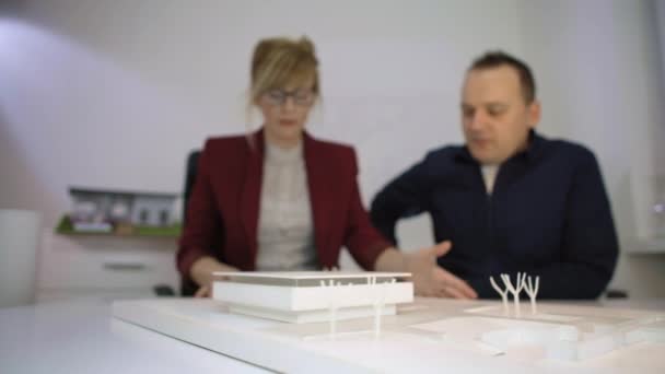 Два Архитектора Офисе Сидят Столом Смотрят Модель Дома Вращают Обсуждают — стоковое видео
