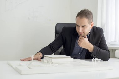 Ofiste işadamı yakından modern bir ev modeli mimarisi bakıyor