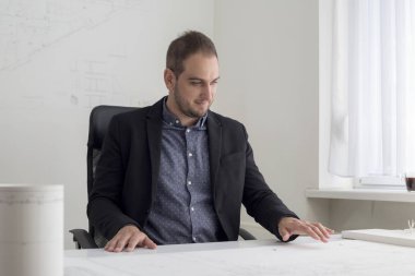 Ofiste işadamı modern bir evin planı yakından bakıyor