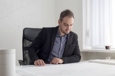 Ofiste işadamı modern bir evin planı yakından bakıyor