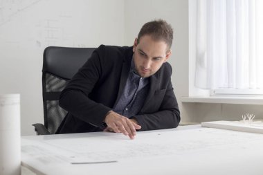 Ofiste işadamı modern bir evin planı yakından bakıyor