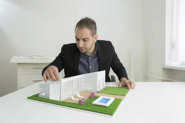 Бизнесмен фиксирует архитектуру модели дома с крышей — стоковое фото