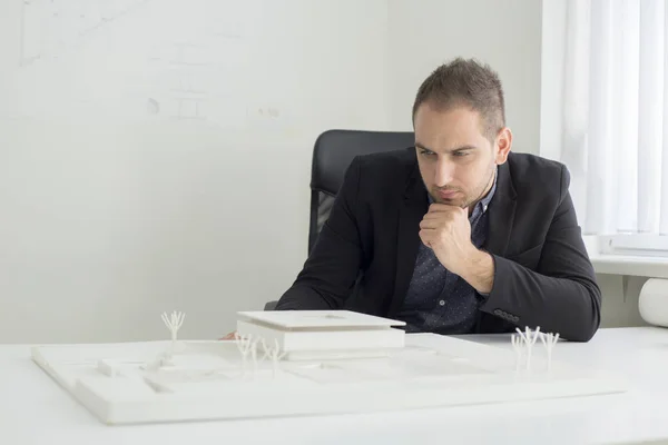 Affärs mannen på kontoret tittar noga in i arkitekturen i en modern hus modell — Stockfoto