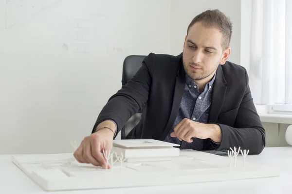 Бизнесмен в офисе внимательно изучает архитектуру современной модели дома — стоковое фото