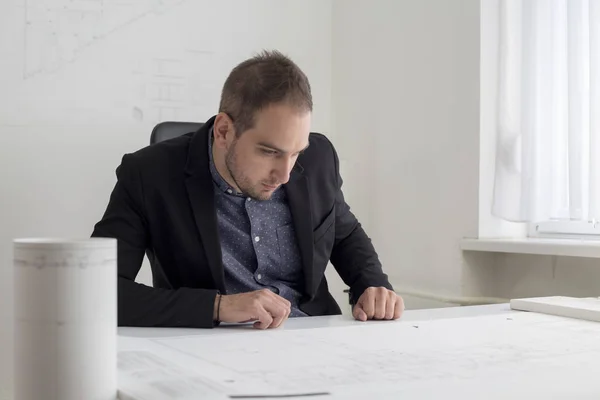Бизнесмен в офисе внимательно изучает чертеж современного дома — стоковое фото