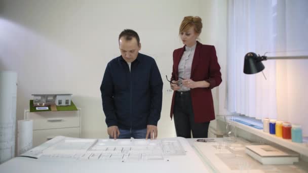 Δύο Αρχιτέκτονες Στο Γραφείο Κοιτάζοντας Ένα Σχέδιο Ενός Σπιτιού Σπίτι — Αρχείο Βίντεο