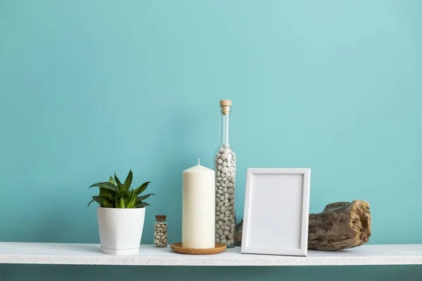 사진 프레임 모형과 현대적인 방 장식입니다. 파스텔 청록색 벽에 촛불과 바위가 있는 흰색 선반. 화분에 심은 뱀 식물 — 스톡 사진