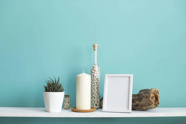 사진 프레임 모형과 현대적인 방 장식입니다. 파스텔 청록색 벽에 촛불과 바위가 있는 흰색 선반. 화분에 심은 즙이 많은 식물 — 스톡 사진