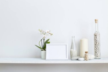 Dekoratif mum, cam ve kayalar ile beyaz duvara karşı Raf. Saksılı orkide bitkisi.