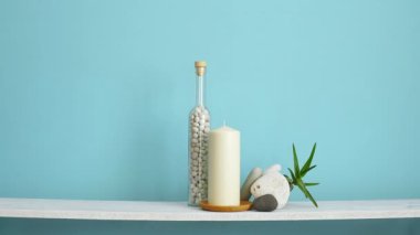 Çerçeve mockup ile modern oda dekorasyonu. Mum ve şişe kayalar ile pastel turkuaz duvara karşı beyaz raf. Boş resim çerçevesi aşağı koyarak.