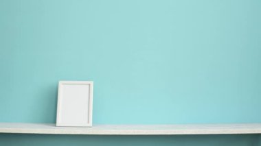Resim çerçevesi mockup ile modern oda dekorasyonu. El saksı kaktüs bitki sakoyan pastel turkuaz duvara karşı beyaz raf.