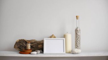 Resim çerçevesi mockup ile modern oda dekorasyonu. Dekoratif mum, cam ve kayalar ile beyaz duvara karşı Raf. El saksı sulu bitki aşağı koyarak.