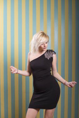 Çizgili sarı mavi arka plan önünde poz çekici genç sarışın kadın