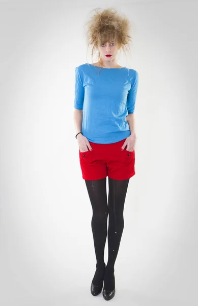 Portrait complet de femme posant en short rouge et pull bleu avec une coiffure folle. Studio de mode tourné - Image — Photo
