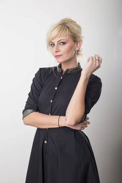 Portrait intérieur de belle femme blonde vêtue d'une robe sombre. Fille posant sur fond blanc — Photo