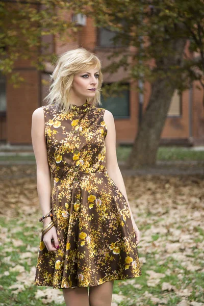 Attrayant robe de mode fille blonde posant dans les feuilles d'automne tomber environnement de style — Photo