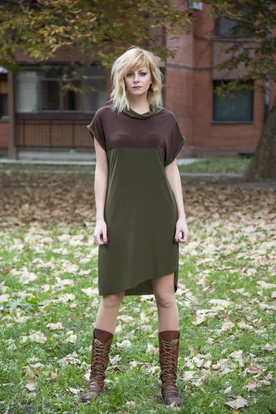 Atractivo vestido de moda chica rubia posando en otoño hojas caída estilo entorno — Foto de Stock