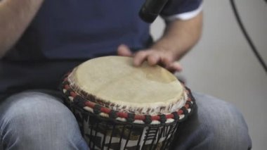 Evde dijital stüdyoda djembe davul enstrümanı kayıt profesyonel müzisyen yakın. O aletleri ve midi denetleyici ile çevrilidir. Müzik prodüksiyon konsepti. 