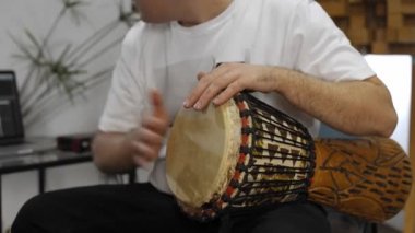 Evde dijital stüdyoda djembe müzik aleti çalarken bilek ağrısı olan profesyonel müzisyen. O aletleri ve midi denetleyici ile çevrilidir. Sağlık kavramı. 