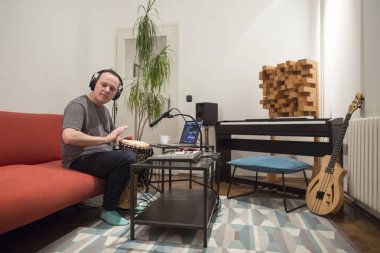 Müzisyen ev müzik stüdyosunda djembe davul enstrümanı çalıyor.