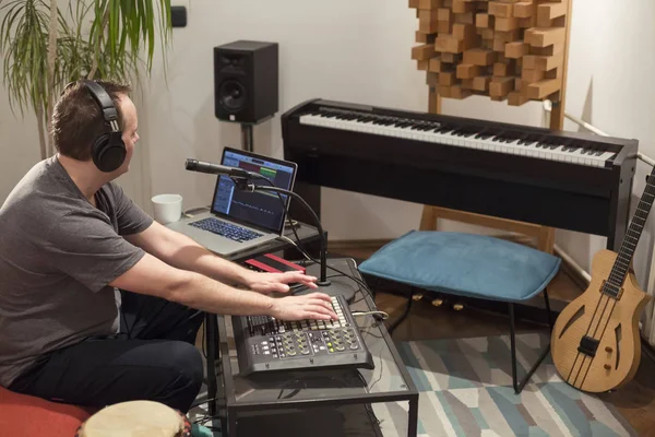 Musician playing midi keyboard in home music studio.