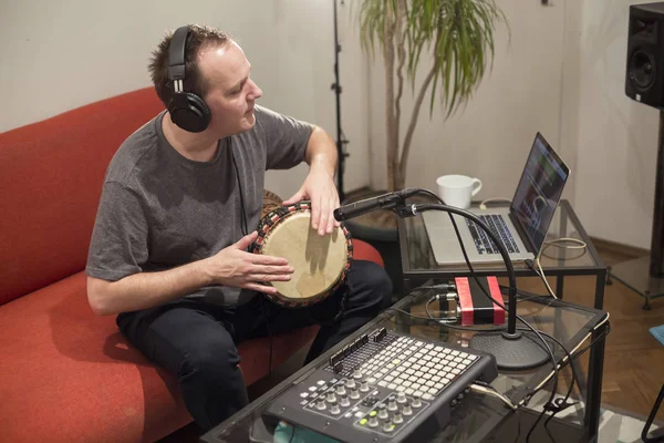Müzisyen ev müzik stüdyosunda djembe davul enstrümanı çalıyor.