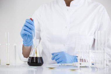 Cam damlalık ve bir kase ile bir laboratuvarda ilaç cbd yağı ile çalışan bilim adamı