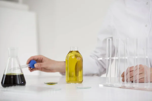 Scienziato che controlla un olio farmaceutico cbd in un laboratorio con contagocce e tubi di vetro — Foto Stock