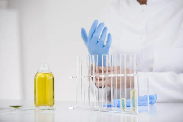 Scienziato che lavora con olio farmaceutico cbd in un laboratorio mettendo guanti — Foto Stock