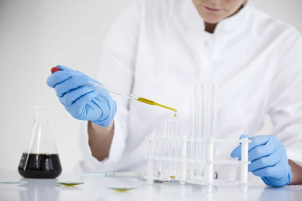 Tudós dolgozik gyógyszerészeti CBD olajat egy laboratóriumban üveg Cseppszámláló és egy tálba — Stock Fotó