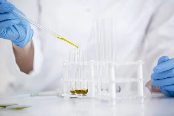 Tudós dolgozik gyógyszerészeti CBD olajat egy laboratóriumban üveg Cseppszámláló és egy tálba — Stock Fotó