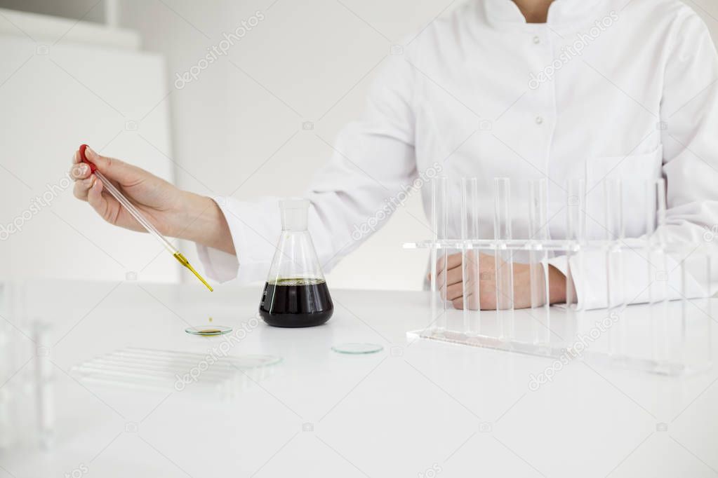 Scientist with gloves checking a pharmaceutical cbd oil in a laboratory on watch glass