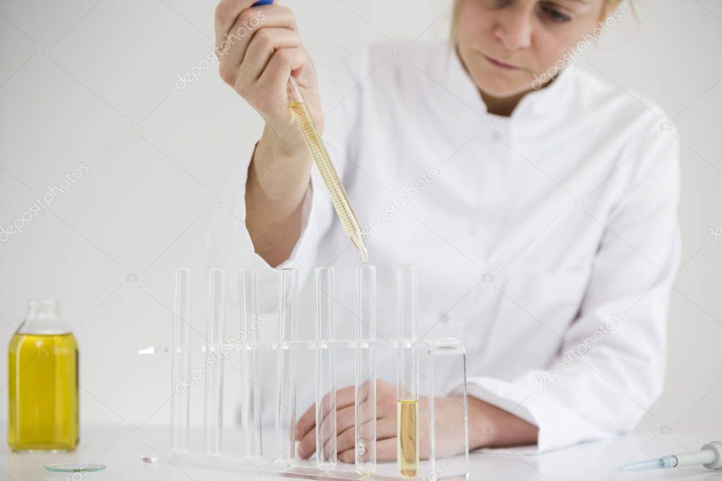 Scientist checking a pharmaceutical cbd oil in a laboratory with glass dropper and tubes