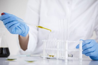 Cam damlalık ve bir kase ile bir laboratuvarda ilaç cbd yağı ile çalışan bilim adamı