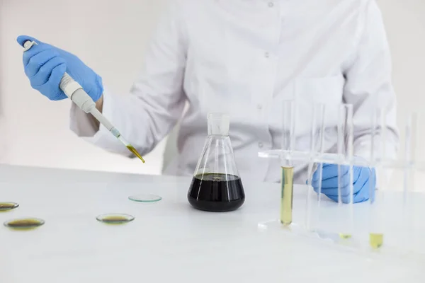Wissenschaftler mit Handschuhen bei der Überprüfung eines pharmazeutischen cbd-Öls in einem Labor auf Uhrglas — Stockfoto