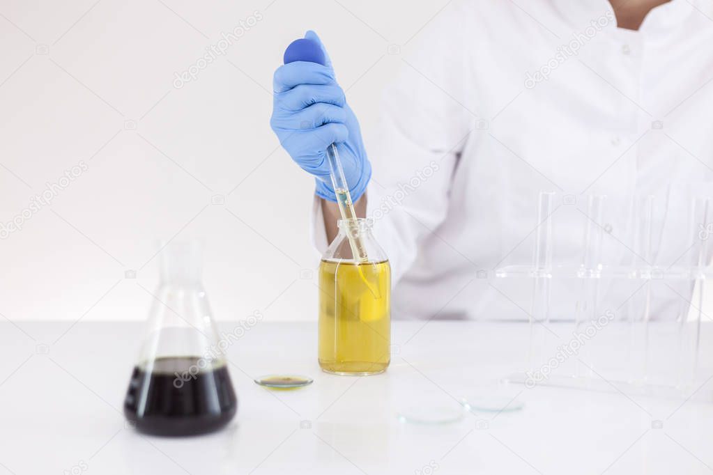 Scientist working with pharmaceutical cbd oil in a laboratory with glass dropper and a bowl