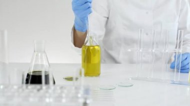 Laboratuvarda kadın bilim adamı bir marihuana bitkisinden çıkarılan Cbd petrolünü test ediyor. O bir cam damlalık ve deney için bir tüp kullanıyor. Tıbbi kenevir gelen sağlık eczane.
