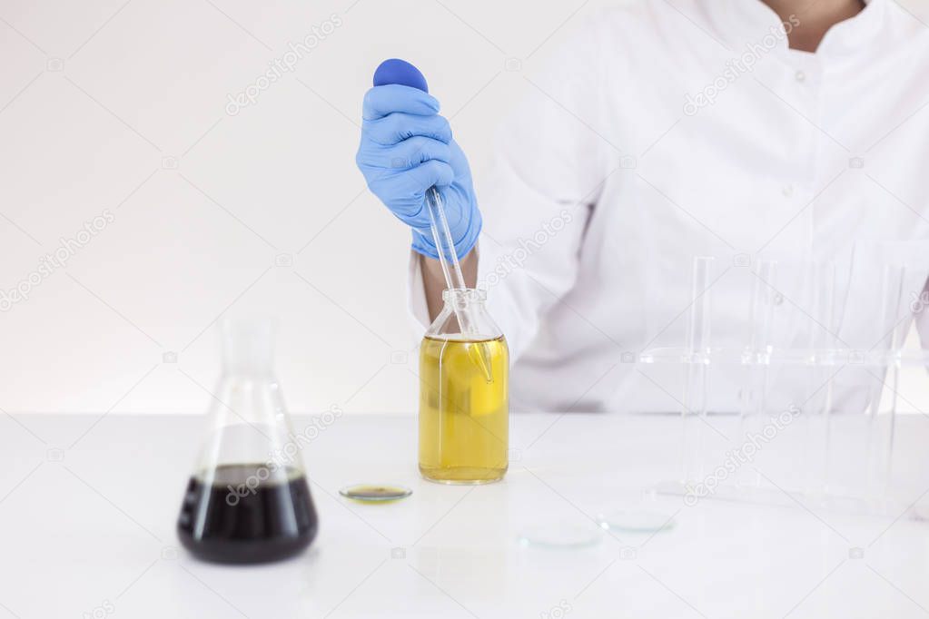 Scientist working with pharmaceutical cbd oil in a laboratory with glass dropper and a bowl