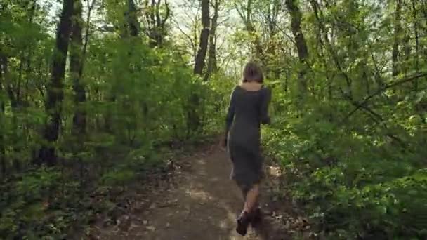 年轻迷人的女人在灰色的衣服走槽厚厚的森林和蔓延的手 女性商品太阳镜和享受好天气 — 图库视频影像