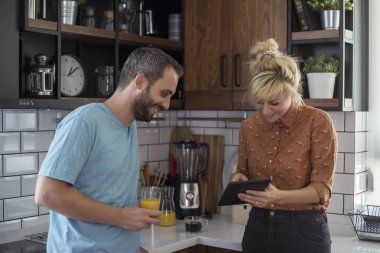 Sabah mutfakta bir çift. Tablette bir şey izlerken eğleniyorlar..