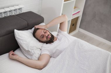 Adam yatak odasında uyanma ve gözlerini ovuşturarak